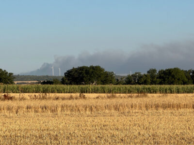 Rauch steigt hinter den Windrädern auf