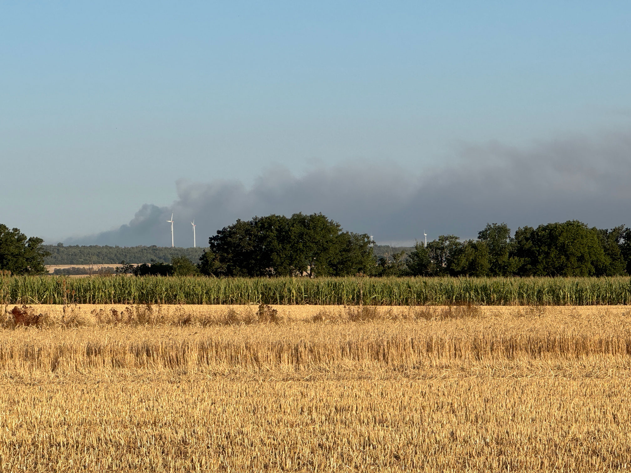 Rauch steigt hinter den Windrädern auf